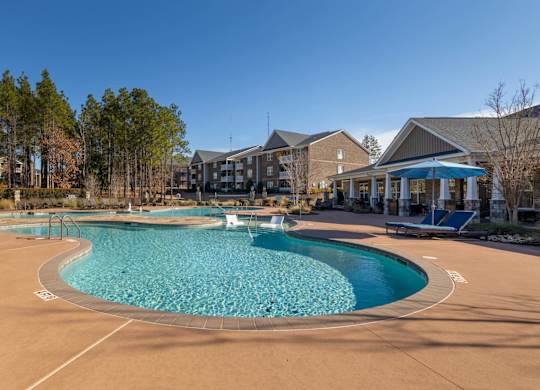 A large outdoor swimming pool with a curved edge and a small waterfall in the middle.
