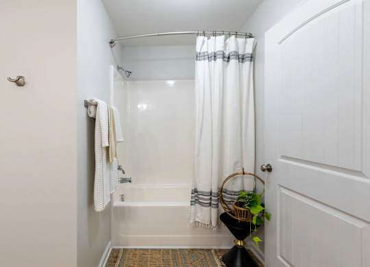 A white bathroom with a white tub and a white shower curtain.