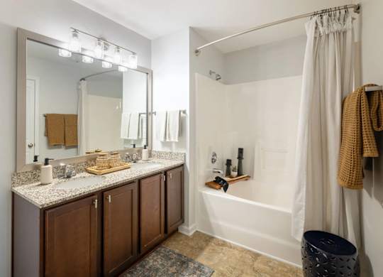 A bathroom with a large mirror, a sink, and a bathtub.