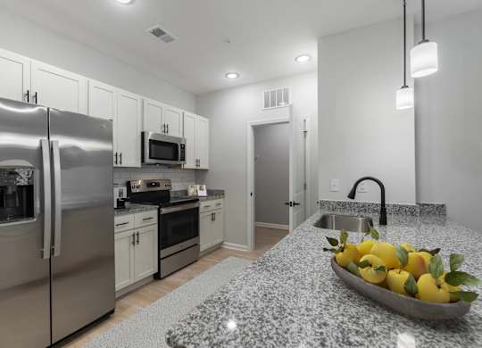 A kitchen with a granite countertop and a bowl of lemons on it.