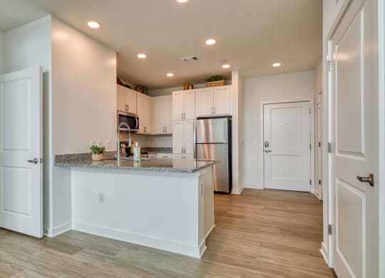a kitchen with white cabinets and a granite counter top and a refrigerator at Allure at Edinburgh, Virginia