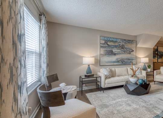 A living room with a large painting on the wall and a white couch.