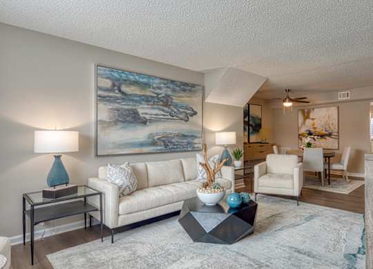A living room with a large painting on the wall and a white couch.