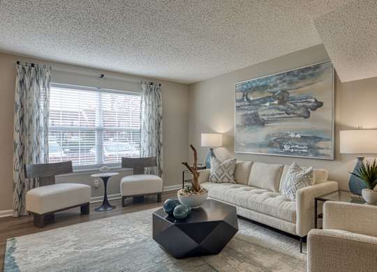 A living room with a large painting on the wall and a white sofa.