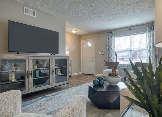 A living room with a flat screen TV and a glass table.