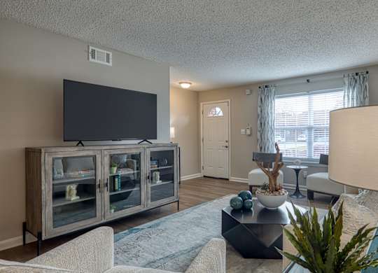 A living room with a television, a glass cabinet, a couch, and a coffee table.