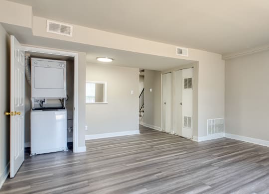 an empty living room with a refrigerator and a washer and dryer