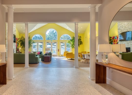 The lobby with white columns and yellow walls and a large window at the end of the