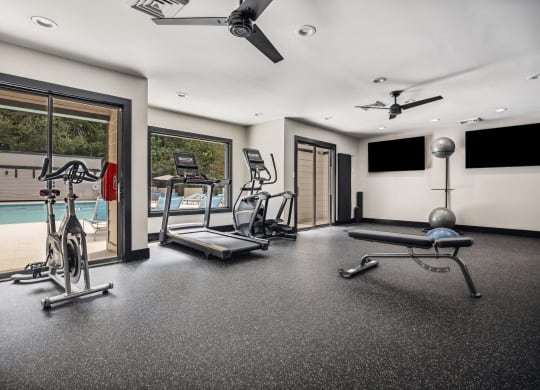 a home gym with a pool in the background
