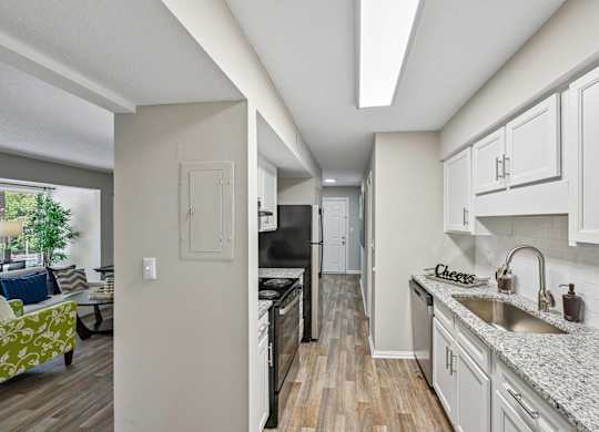 A kitchen with a black refrigerator and white cabinets.