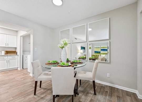 A dining room with a table set for two and a kitchen area in the background.