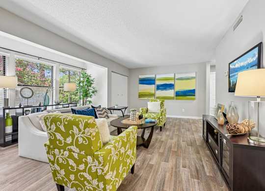 A living room with a green patterned chair and a painting on the wall.