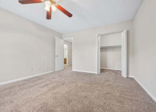 A room with a ceiling fan and carpeted floor.