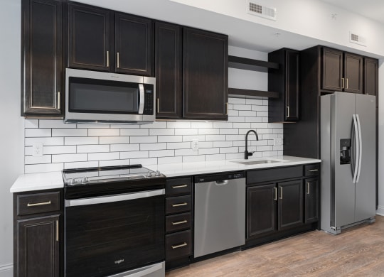 a kitchen with black cabinets and a stainless steel refrigerator at The Madison, Columbus, OH, 43215