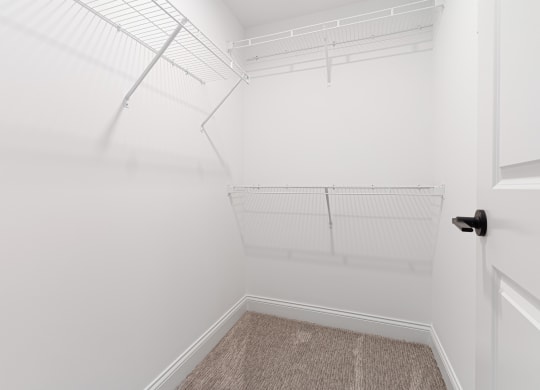 a walk in closet with white walls and white shelves and a white door at The Madison, Columbus, Ohio