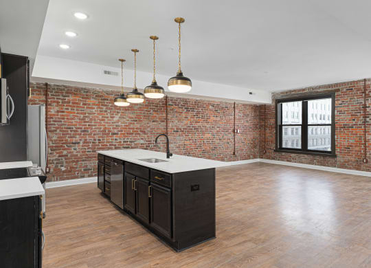 the kitchen has a large island with a sink and a brick wall at The Madison, Columbus, Ohio