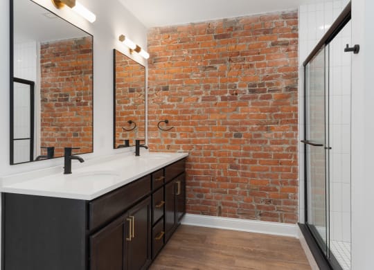 a bathroom with a brick wall and a sink and a mirror at The Madison, Columbus, OH, 43215