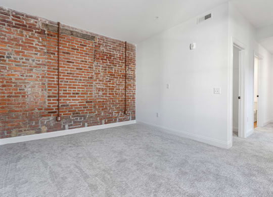 an empty room with a brick wall and white carpet at The Madison, Columbus