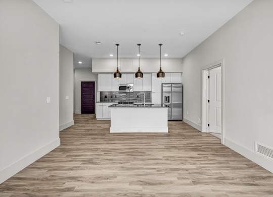A modern kitchen with a white island and pendant lights.