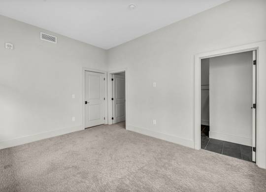 A room with a carpeted floor and two doors.