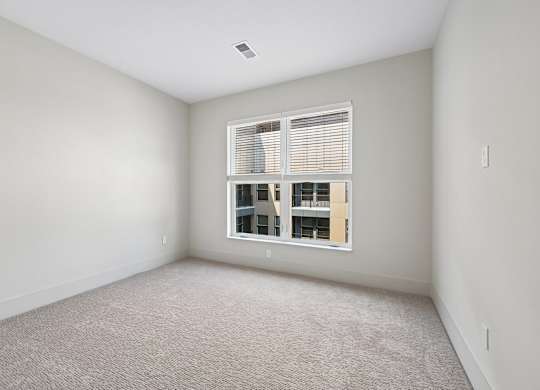 A room with a window and a carpeted floor.