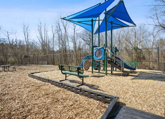 a playground with a slide and benches in a park