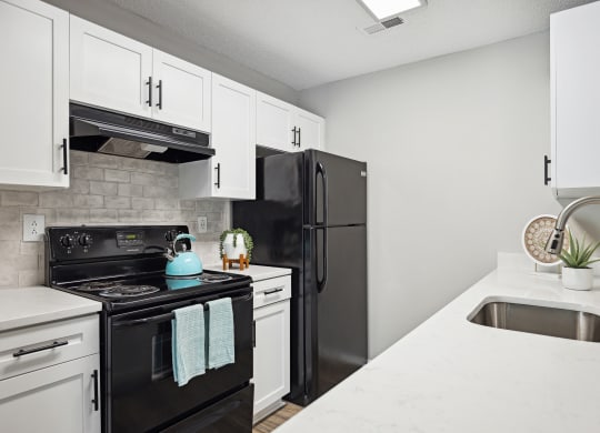 an apartment kitchen with black appliances and white cabinets