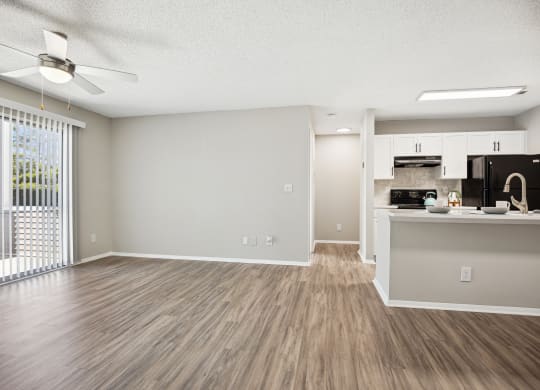 an empty living room with a kitchen and a window