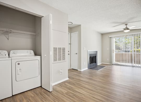 the living room and laundry room of an apartment with a washer and dryer