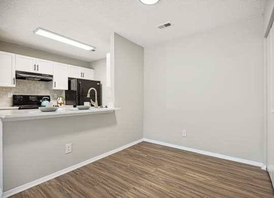an empty kitchen and living room with white walls and wood flooring