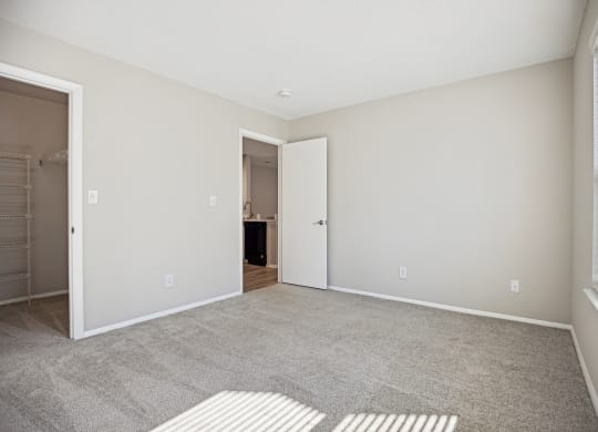 an empty living room with a large window and a door to a bathroom