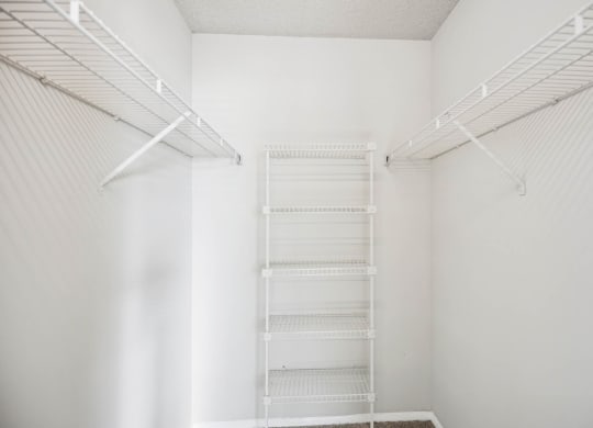 a walk in closet with white walls and a white shelving unit