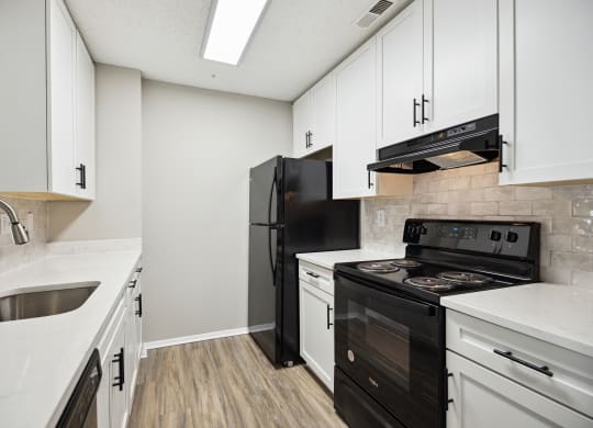 an empty kitchen with white cabinets and a black stove and refrigerator