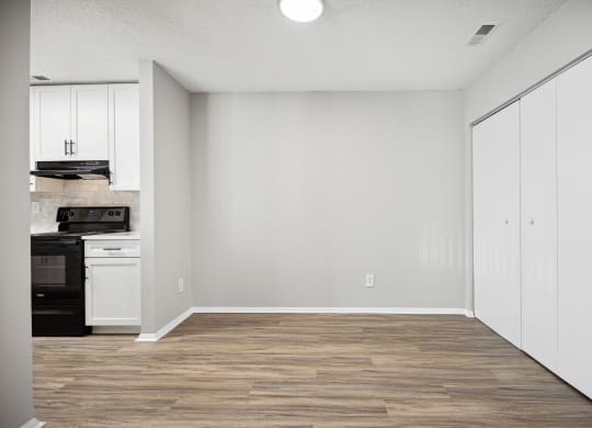 an empty kitchen with white cabinets and a wood floor