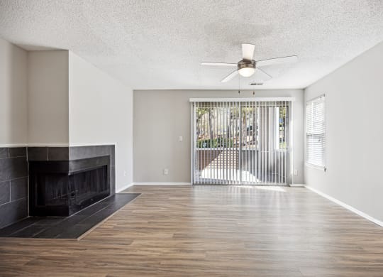 an empty living room with a fireplace and a ceiling fan