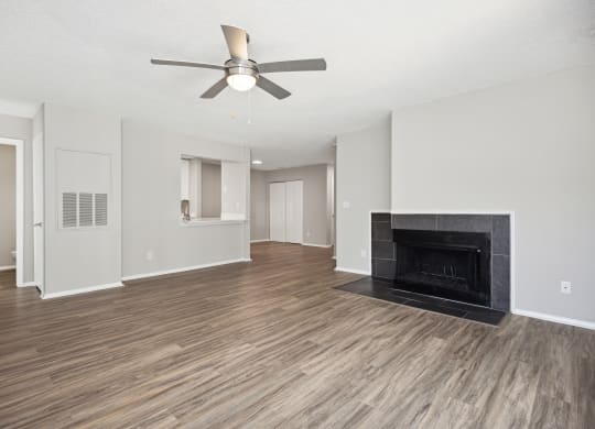 an empty living room with a fireplace and a ceiling fan