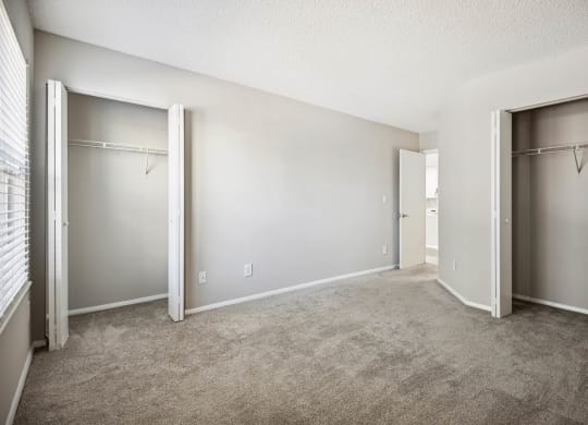 an empty bedroom with closet doors and carpeting