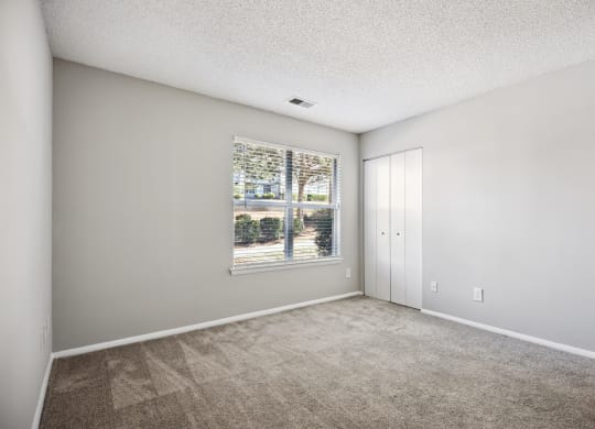 an empty living room with a large window and carpeting