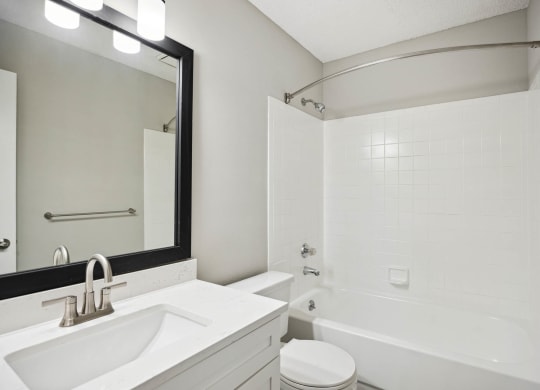 a white bathroom with a sink and a tub and a mirror