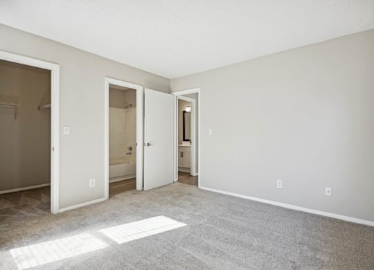 an empty living room with white walls and a door to a bathroom