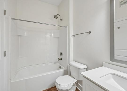 A white bathroom with a toilet, sink, and bathtub.