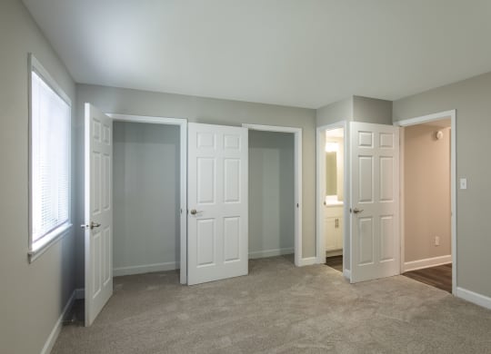a bedroom with three doors and a carpeted floor