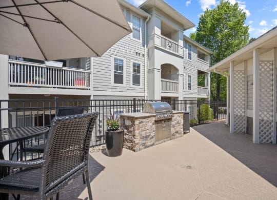 a patio with a grill and a table and chairs