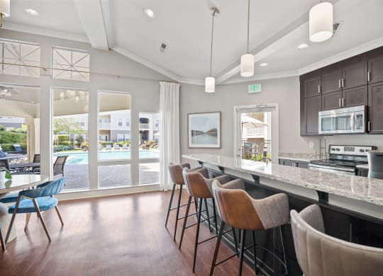 a kitchen with a bar and chairs in front of a window