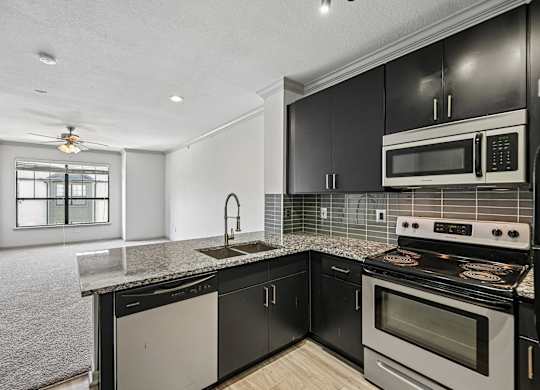 A modern kitchen with black cabinets and a white stove top oven.