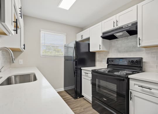 an empty kitchen with white cabinets and black appliances