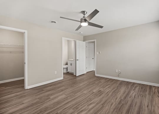 an empty living room with a ceiling fan and a bathroom