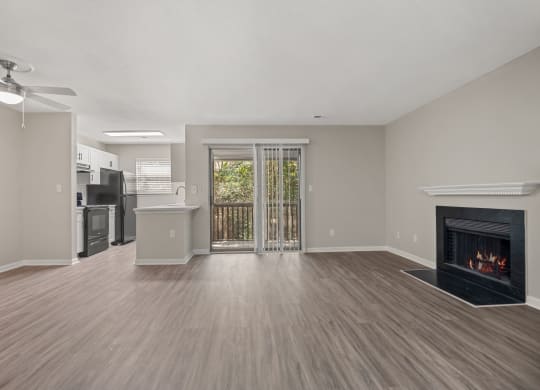 an empty living room with a fireplace and a kitchen