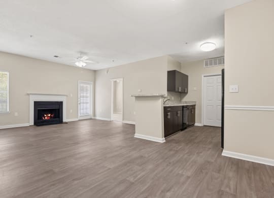 an empty living room with a fireplace and a kitchen