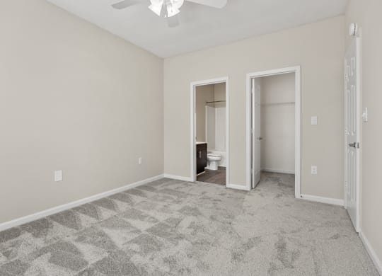 an empty living room with a ceiling fan and a door to a bathroom